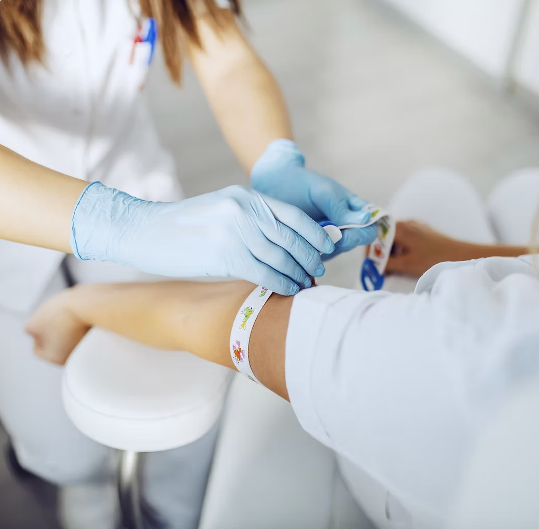 WellDraw Mobile Phlebotomy technician in navy scrubs with the WellDraw logo